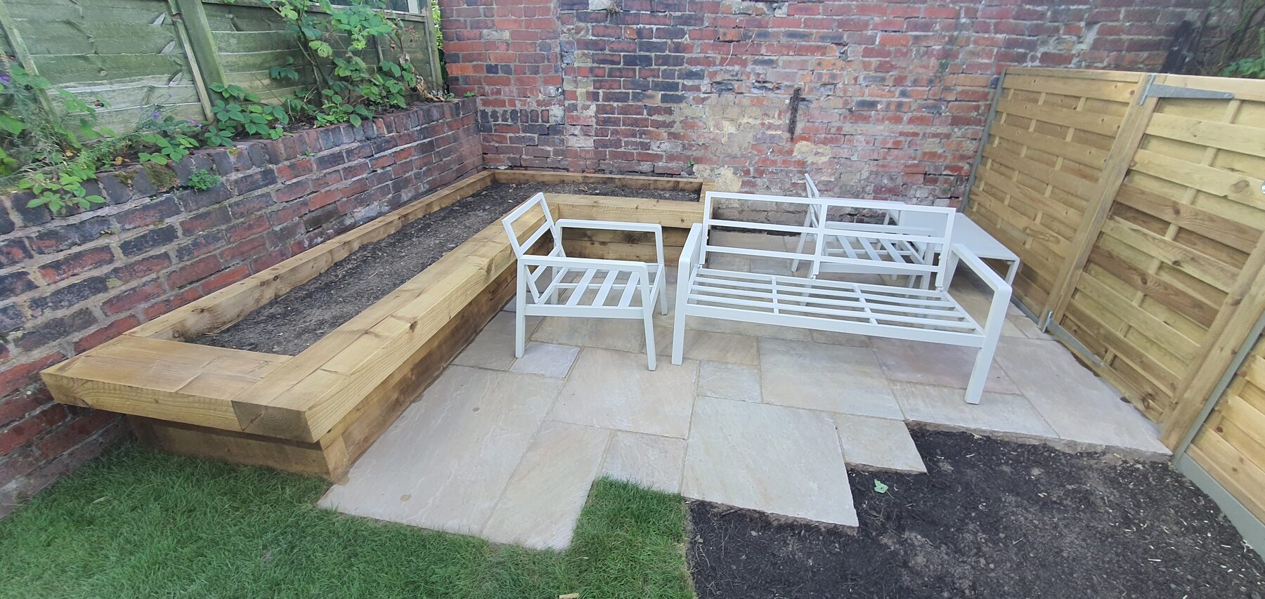 Finished corner patio with timber seating edge, bench and planting beds