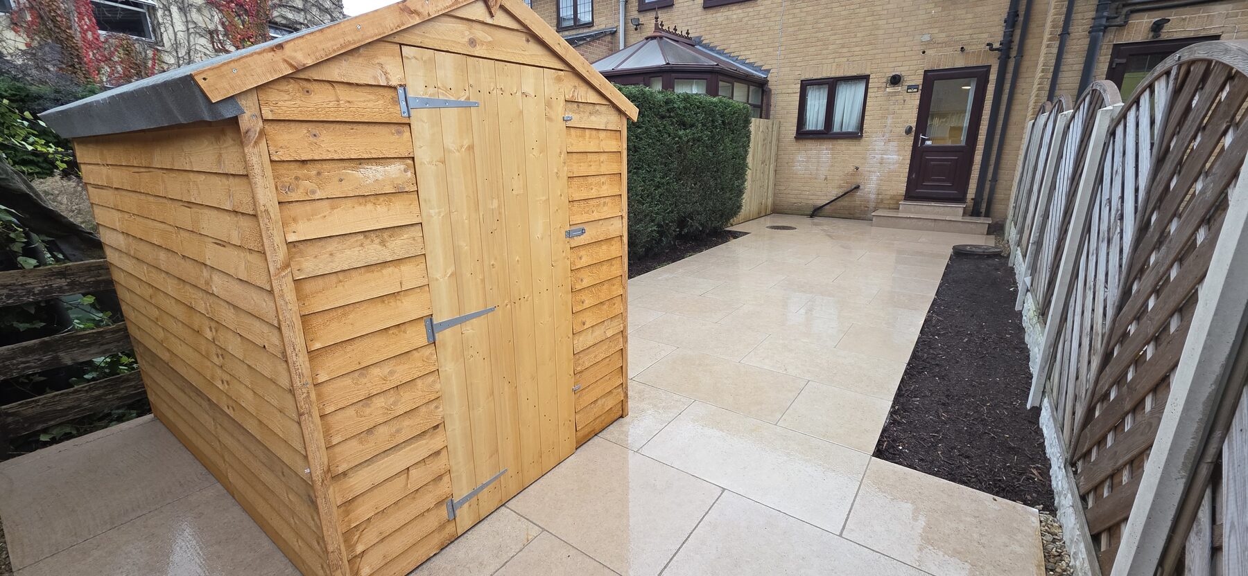 Completed Sahara Pearl garden project: garden with Sahara Pearl paving, planting beds, a retained hedge and garden shed, view 2