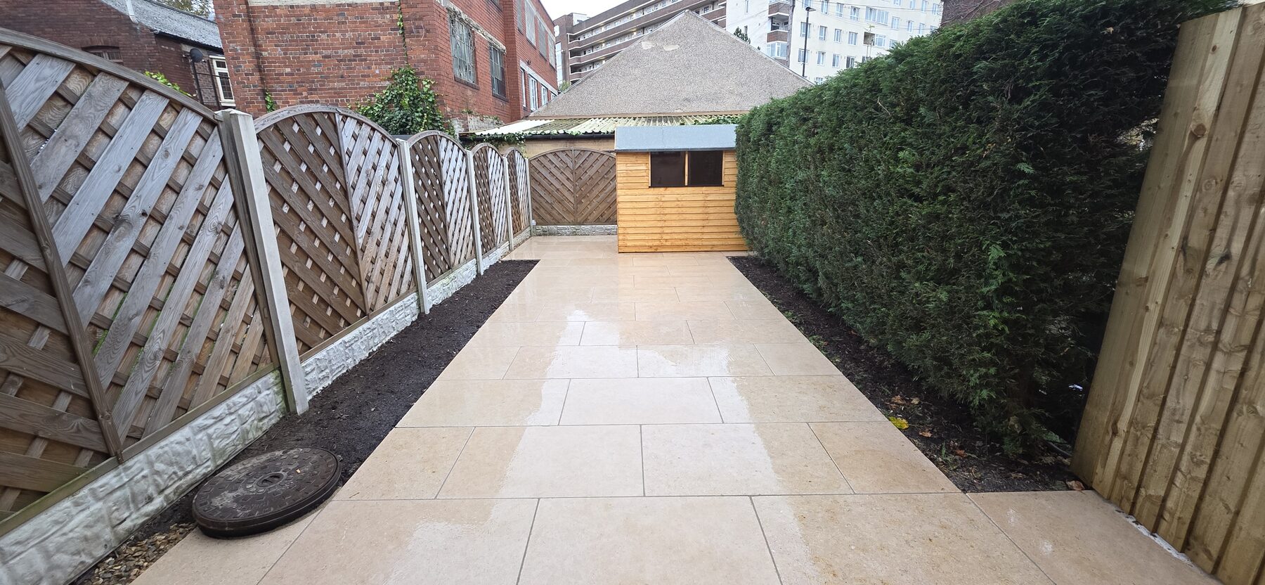 Completed Sahara Pearl project: garden with Sahara Pearl paving, planting beds, a retained hedge and garden shed